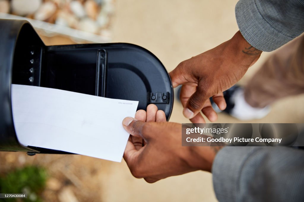 Man removing an envelope from his mailbox