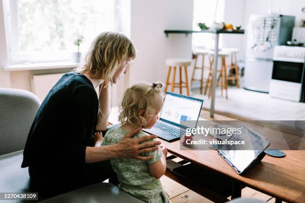 young mother holds a virtual meeting from home office while her child watches cartoons on digital tablet - children looking graph stock pictures, royalty-free photos & images