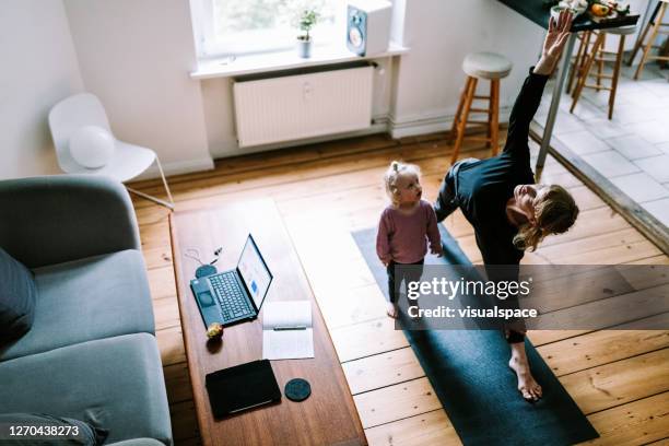 young mother does a side plank yoga pose while her daughter observes her - child yoga elevated view stock pictures, royalty-free photos & images