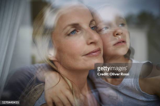 mother and son looking out of window together - anticipation face stock pictures, royalty-free photos & images
