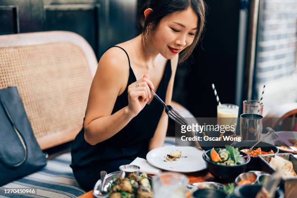 young woman eating food at the restaurant - luxus essen stock-fotos und bilder