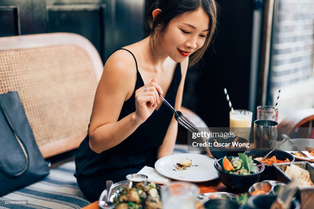 Young Woman Eating Food At The Restaurant