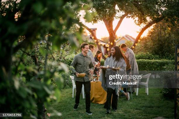 smiling male and female talking in yard during dinner party - gartenparty stock-fotos und bilder