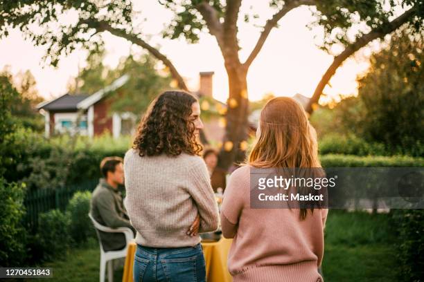 rear view of female friends talking in yard for social gathering - the party arrivals stock-fotos und bilder