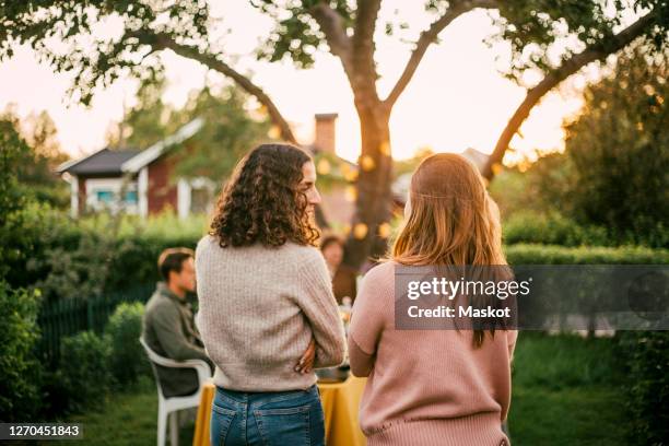 rear view of female friends talking in yard for social gathering - back yard photos et images de collection