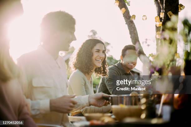 cheerful female with friends sitting in backyard at garden party - kleine personengruppe stock-fotos und bilder