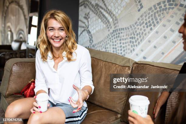 eine blonde frau mit einem hübschen lächeln sitzt in einem café mit einem freund - elegant woman smile stock-fotos und bilder