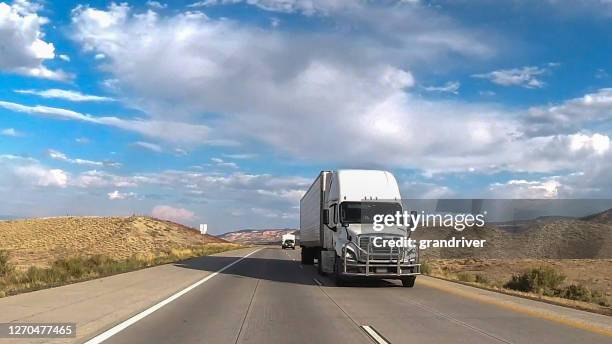 long-haul semi trailer truck big rig moving on a four-lane highway under a dramatic sunset cloudscape in the american west - west front stock pictures, royalty-free photos & images