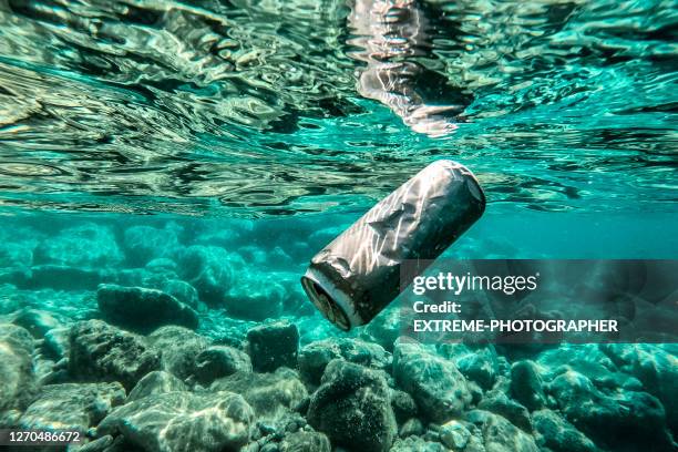a can thrown in the water - sea pollution stock pictures, royalty-free photos & images