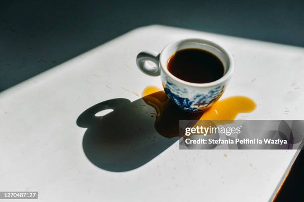 espresso cup filled with spilled coffee around - verschütten stock-fotos und bilder
