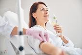 Attractive dark-haired woman smiling during the intravenous therapy