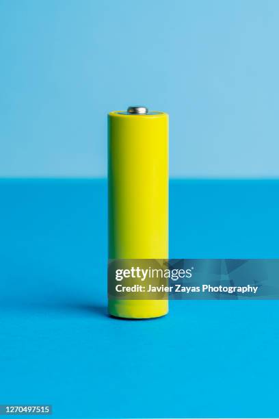 yellow battery on blue blackground - cylinder stock pictures, royalty-free photos & images