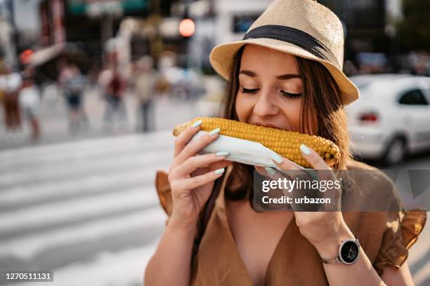 woman eating corn on the street - espiga de milho imagens e fotografias de stock