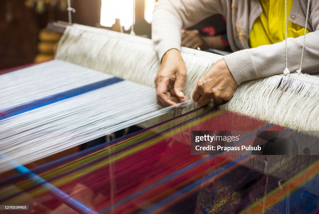 Close up of woman weaving silk from hand weaving machine, Abstract background - selective focus, Thailand