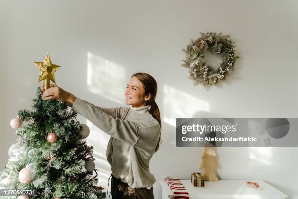 young woman decorating the christmas tree - christmas angel stock pictures, royalty-free photos & images