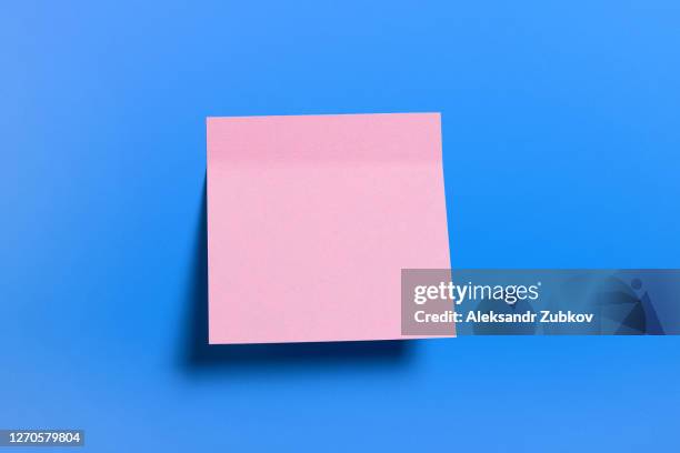 pink sticky sticker for informational reminder, on a blue background. space for text. - kleverig stockfoto's en -beelden