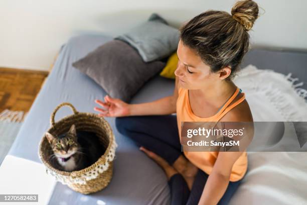 femme détendu avec le chat pratiquant le yoga à la maison - chat yoga photos et images de collection