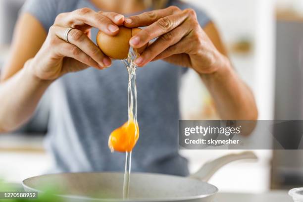 sluit omhoog van een vrouw die een ei kraakt. - animal egg stockfoto's en -beelden