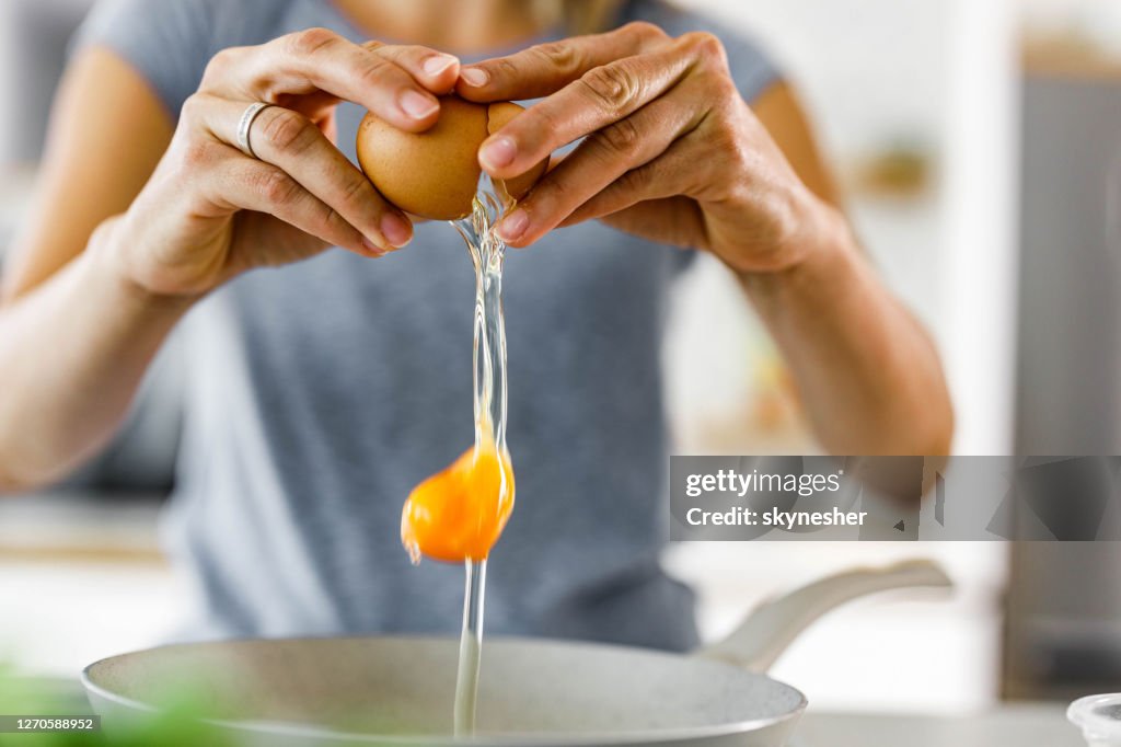 Close up of a woman cracking an egg.