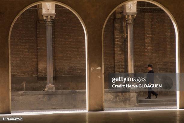 Un homme en costume noir marche le long des arcades place Prato della Valle, aout 1974, Padoue, Italie.