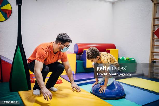 garçon exerçant avec le kinésithérapeute dans la pièce sensorielle - sensory perception stock photos et images de collection
