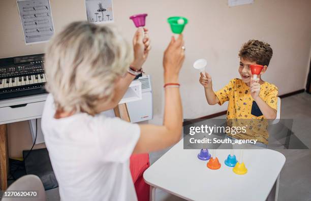 boy with female teacher on music class - music therapy stock pictures, royalty-free photos & images