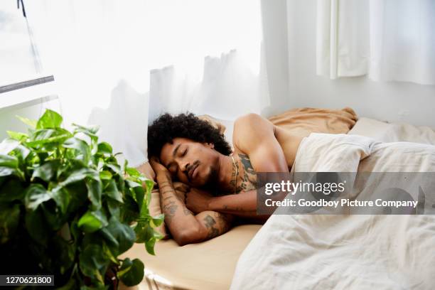 young man lying asleep in his bed at home - lying on side stock pictures, royalty-free photos & images