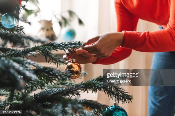 weibliche hände schmücken weihnachtsbaum mit goldenen retro weihnachtskugel - decoration stock-fotos und bilder