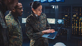 International Team of Military Personnel Have Meeting in Top Secret Facility, Female Leader Holds Laptop Computer Talks with Male Specialist. People in Uniform on Strategic Army Meeting