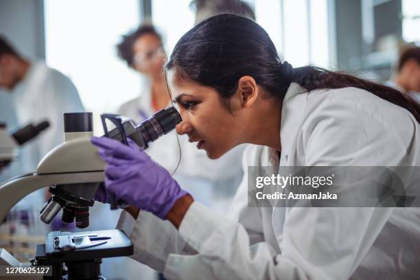 estudante universitário indiano usando microscópio em laboratório - purple glove - fotografias e filmes do acervo