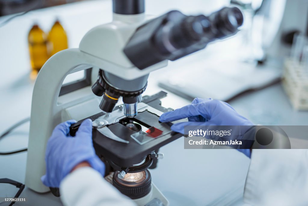 Diapositiva de microscopio de manejo de estudiantes de la universidad femenina en el laboratorio