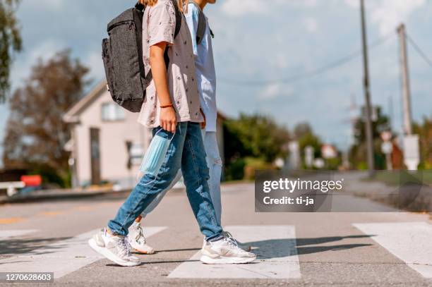 two schoolgirls crossing the street - cross road children stock pictures, royalty-free photos & images