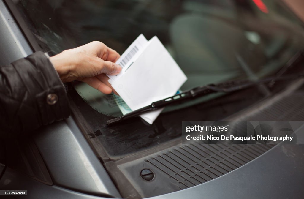 Close-up of human hand taking parking ticket from car