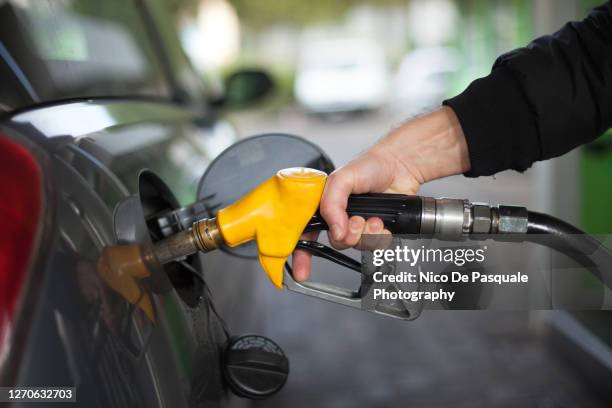 close-up of hand holding fuel nozzle - fossil fuel stock pictures, royalty-free photos & images