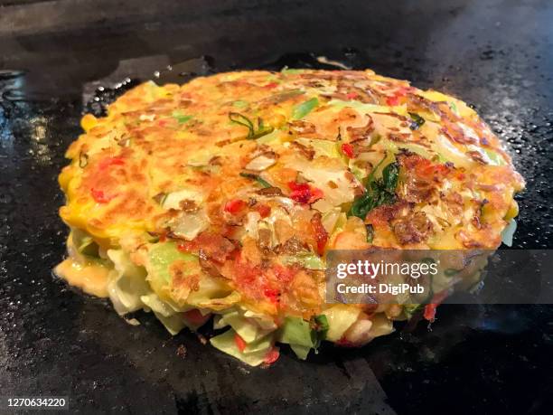 okonomiyaki being cooked over griddle - okonomiyaki 個照片及圖片檔