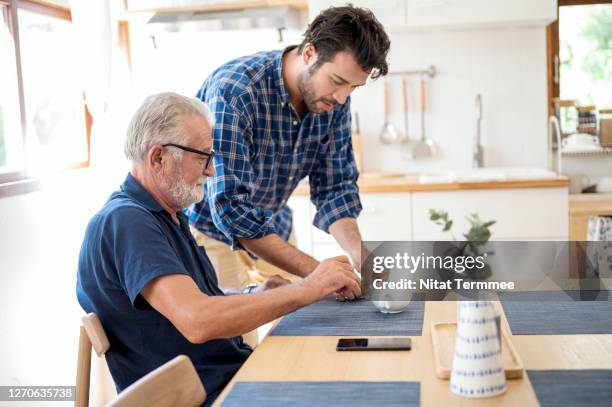 caucasian son service soup to elderly father in morning breakfast. health care, assisted living. - assisted living stock-fotos und bilder