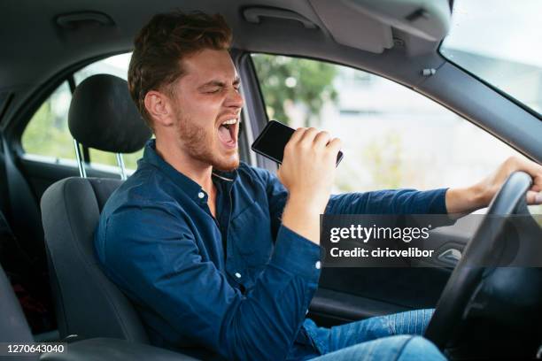 young man driving and singing - mobile phone in hand driving stock pictures, royalty-free photos & images