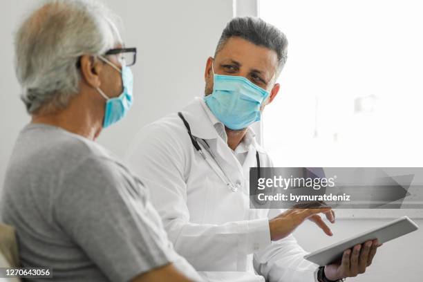 doctor using digital tablet and talking to patient at home - visit stock pictures, royalty-free photos & images