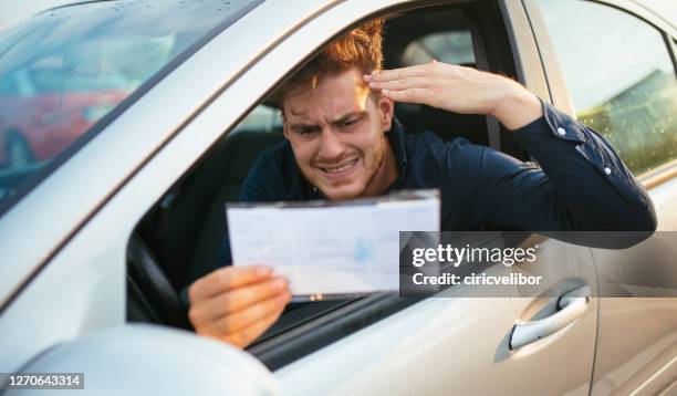 gut aussehender junger mann bekommt parkschein - parkvergehen-strafzettel stock-fotos und bilder