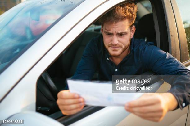 upset young man gets parking ticket - tráfego imagens e fotografias de stock
