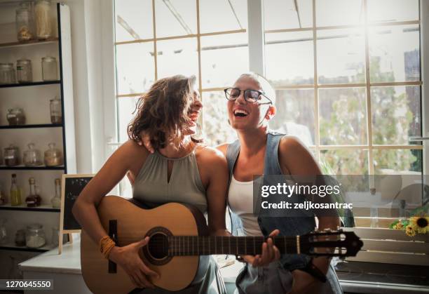 two girl friends playing guitar home - couple singing stock pictures, royalty-free photos & images