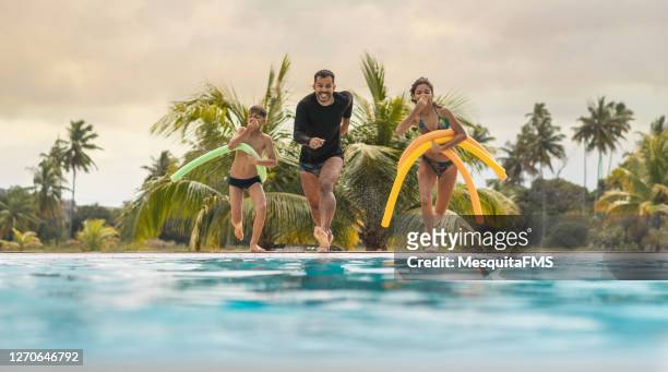 father and children jumping in the pool - swimming pool jump stock pictures, royalty-free photos & images