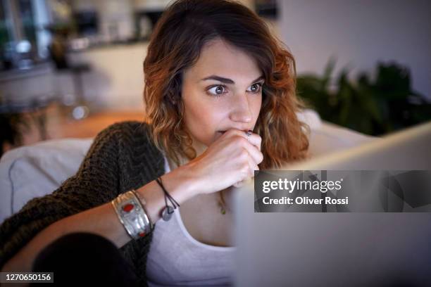 excited woman sitting on couch looking at laptop - staring up stock pictures, royalty-free photos & images