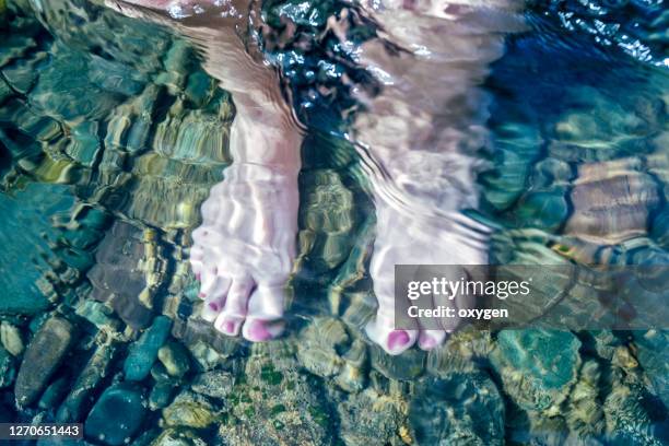 feet underwater on the stones down of woman's bare feet. selfie in the water, top view - womans bare feet fotografías e imágenes de stock