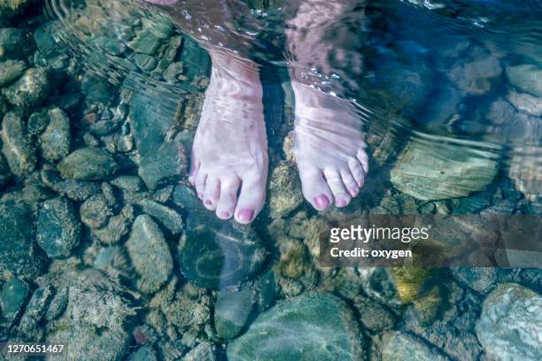 feet underwater on the stones down of woman's bare feet. selfie in the water, top view - feet selfie woman stockfoto's en -beelden
