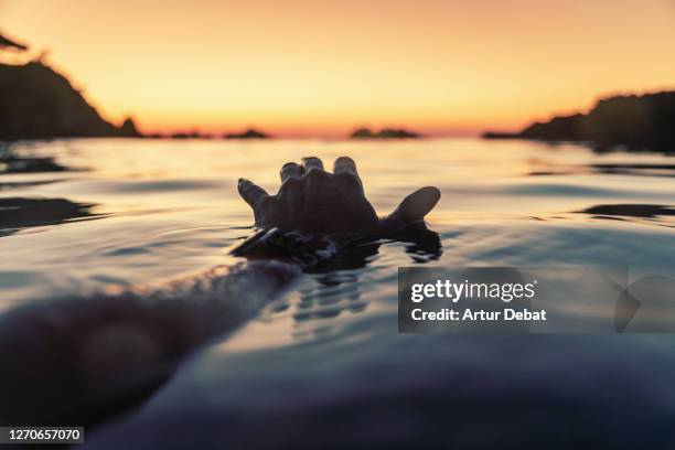 watching sunrise swimming in water from personal perspective with hand touching water in a costa brava beach. - vue subjective main photos et images de collection