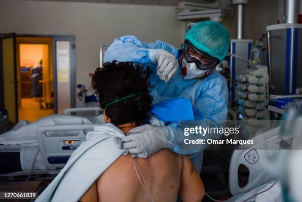 Health worker wears a protective suit, face mask and gloves as he helps a COVID-19 patient during a Physical therapy session at the ICU of Krakow...