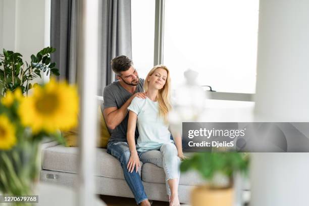 mid adult man giving a shoulder massage to his wife at home. - girlfriend massage stock pictures, royalty-free photos & images