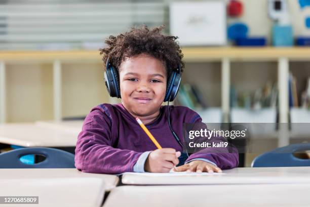 elementaire student die in klasse schrijft, die hoofdtelefoons draagt - 7 stockfoto's en -beelden