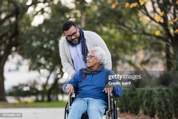 senior hispanic man in wheelchair, with adult son - healthcare worker imagens e fotografias de stock